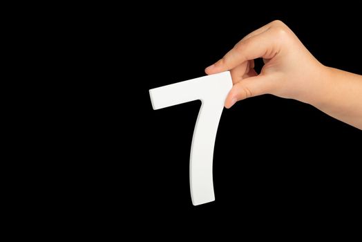 Number seven in hand isolated on black background. Number 7 in a child's hand on a black background. To be inserted into a project or design