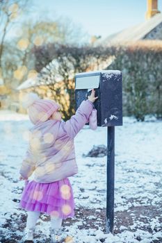 Charming baby throws a letter in the mailbox.