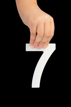 Number seven in hand isolated on black background. Number 7 in a child's hand on a black background. To be inserted into a project or design