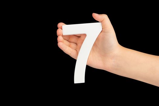 Number seven in hand isolated on black background. Number 7 in a child's hand on a black background. To be inserted into a project or design