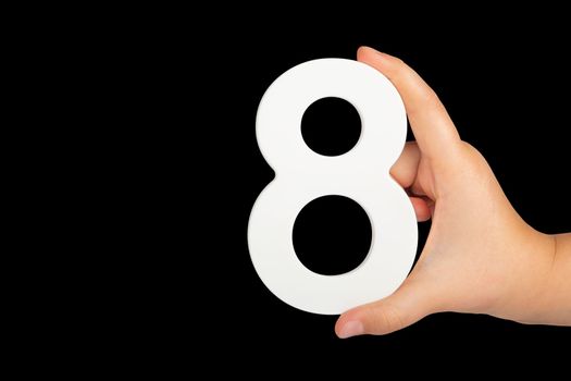 Number eight in hand isolated on black background. Number 8 in a child's hand on a black background. To be inserted into a project or design