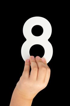 Number eight in hand isolated on black background. Number 8 in a child's hand on a black background. To be inserted into a project or design