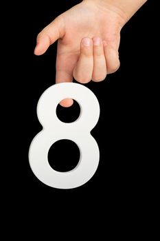 Number eight in hand isolated on black background. Number 8 in a child's hand on a black background. To be inserted into a project or design