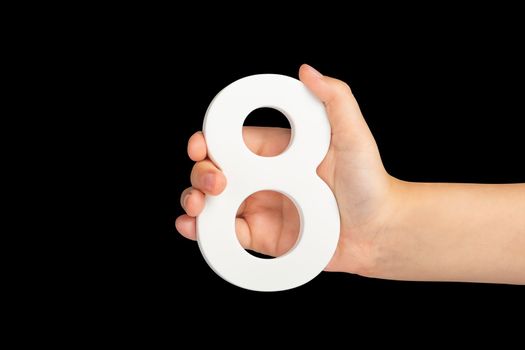 Number eight in hand isolated on black background. Number 8 in a child's hand on a black background. To be inserted into a project or design