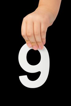 Number nine in hand isolated on black background. Number 9 in a child's hand on a black background. To be inserted into a project or design