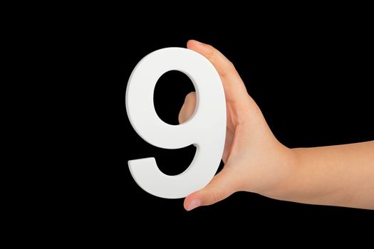 Number nine in hand isolated on black background. Number 9 in a child's hand on a black background. To be inserted into a project or design