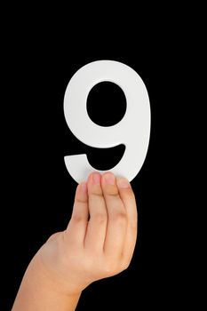 Number nine in hand isolated on black background. Number 9 in a child's hand on a black background. To be inserted into a project or design