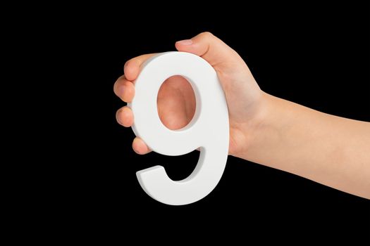 Number nine in hand isolated on black background. Number 9 in a child's hand on a black background. To be inserted into a project or design