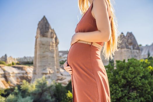 Pregnant woman on background of Unique geological formations in Love Valley in Cappadocia, popular travel destination in Turkey. Fertility concept.