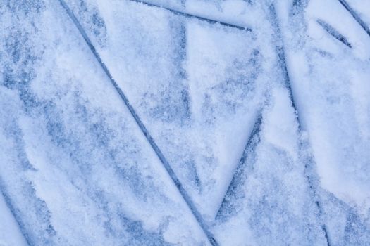 Empty ice rink with skate marks after the session outdoor. skating ice rink texture covered with snow in daylight. Close up of blue ice rink floor, copy space