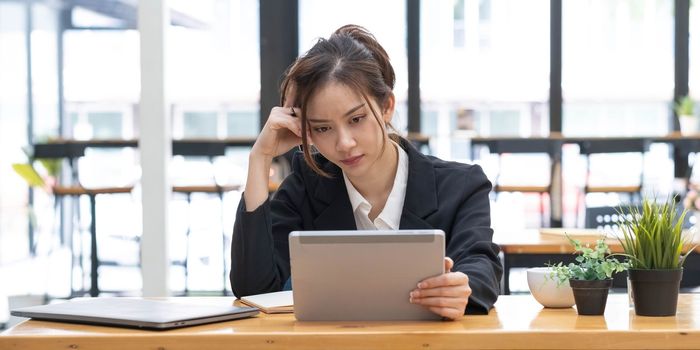 Sad Young woman employee having problems about her debts and financials. Frustrated Asian Beautiful businesswoman feeling depression, exhausted, tired, lazy during working at the office...