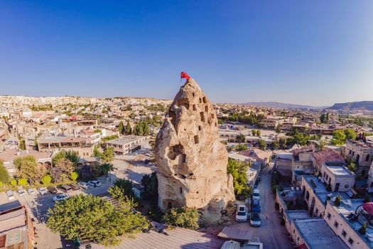 Turkish flag on the hill with typical tuff rock formations of the Cappadocia against the backdrop of a blue sky, Goreme, Turkey.