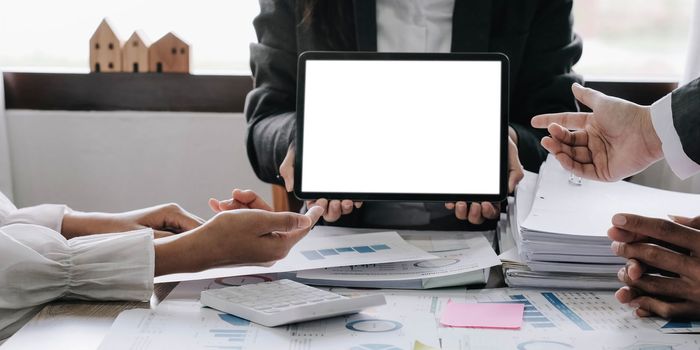 Two businesswomen meet in a meeting room for a business consultation, using a laptop computer and tablet. mockup of a laptop with a blank screen.