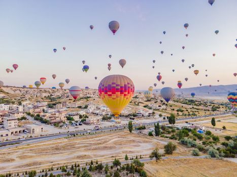 Colorful hot air balloons flying over at fairy chimneys valley in Nevsehir, Goreme, Cappadocia Turkey. Spectacular panoramic drone view of the underground city and ballooning tourism. High quality.