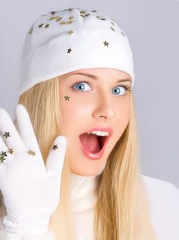 Happy holidays, surprised woman in white hat and gloves. Beauty and fashion model on grey background. Funny blonde girl smiling and enjoying the holidays.