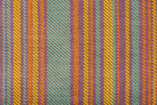 Texture of fabric for furniture upholstery in multicolored vertical stripes. Wear-resistant fabric for furniture in red senin and green patterns. Texture of wear-resistant fabric close-up top view