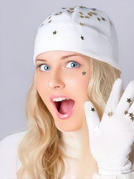 Merry Christmas, good holidays and woman dressed in white hat and gloves. On studio background, beauty and fashion female model. Surprised humorous blonde girl smiles and enjoys the Christmas, New Year, and winter holiday lifestyle.