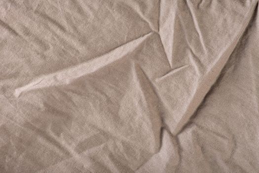 The texture of the crumpled fabric is dark gray. Gray fabric with large folds, top view. For texture or design overlay.
