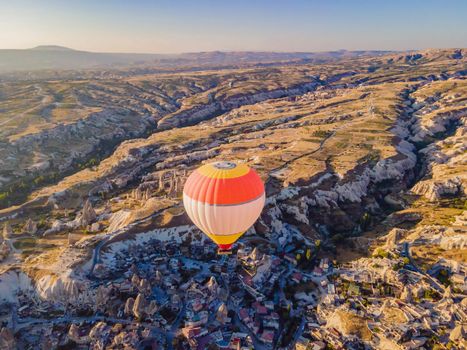 Colorful hot air balloons flying over at fairy chimneys valley in Nevsehir, Goreme, Cappadocia Turkey. Spectacular panoramic drone view of the underground city and ballooning tourism. High quality.