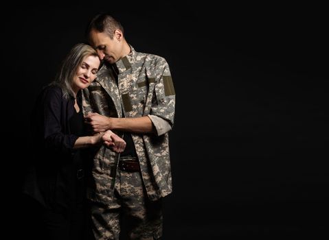 Happy woman hugging his husband came back from army. Smiling cheerful caucasian girlfriend embracing a soldier