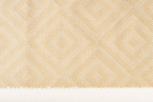 Texture of fabric for furniture upholstery in beige color with rectangular patterns or rhombuses. Texture of wear-resistant fabric for furniture production, close-up, top view