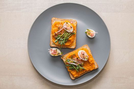 Sandwiches with squash caviar and micro green and quail eggs on a gray plate.