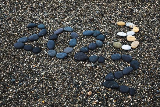 Number 2023 as a New Year concept made from stones on pebble beach. Change from 2022 to 2023