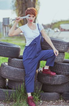 attractive woman mechanic in overalls holding wrench.