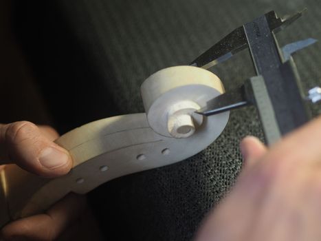 violin maker using a meter to shape and accurate measure fiddle scroll