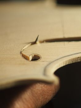violinmaker cutting and sawing golden period cremonese violin model fholes with a blade with precision