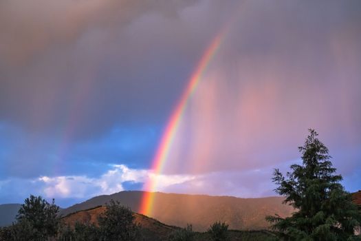 Rays of the sun breaking through the stormy sky, forming a marvelous rainbow. High quality photo