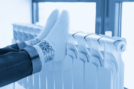 Woman warming up with feet on heater