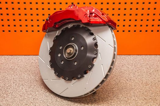 steel brake disc and red sports support lie on the table in the workshop