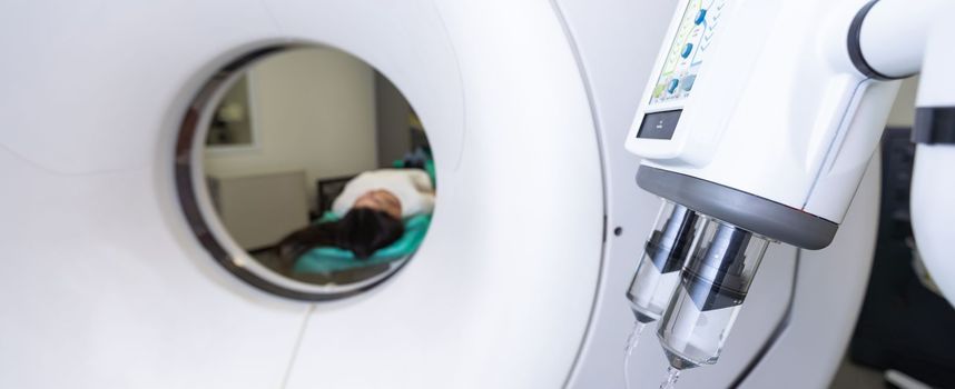 CT scan technologist overlooking patient in Computed Tomography scanner during preparation for procedure. Woman patient going into CT scanner