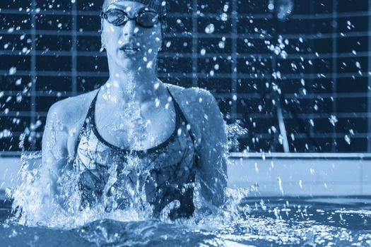 Young professional swimmer swims in an indoor pool with much splashing