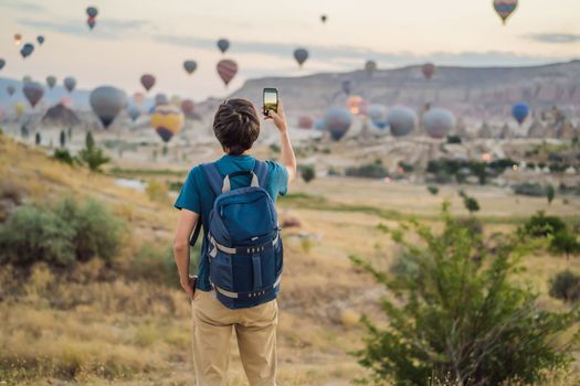 Tourist man looking at hot air balloons in Cappadocia, Turkey. Happy Travel in Turkey concept. Man on a mountain top enjoying wonderful view.