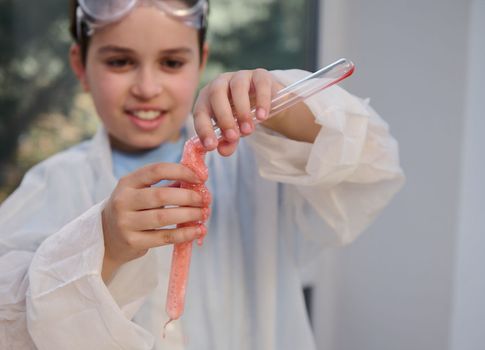 Focus on schoolboy's hands, holding test tubes with ongoing chemical reaction - volcanic eruption. Chemistry class. Back to school. Learning. Science. Education. Knowledge. Young chemist scientist