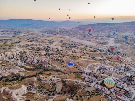 Colorful hot air balloons flying over at fairy chimneys valley in Nevsehir, Goreme, Cappadocia Turkey. Spectacular panoramic drone view of the underground city and ballooning tourism. High quality.