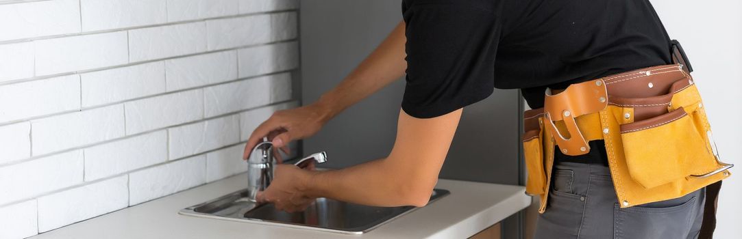 Man installing the kitchen tap and the sink.