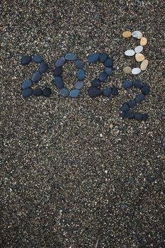 Number 2023 as a New Year concept made from stones on pebble beach. Change from 2022 to 2023