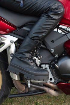 girls feet on the steps of a Honda motorcycle in a beautiful black boot. High quality photo