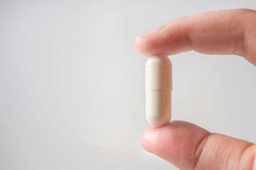 Antibiotics. The concept of antibiotic therapy, drug treatment. Capsule with an antibiotic is clamped in the fingers close-up on a white background. Copy space