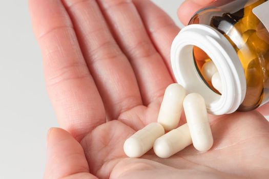 A woman holds pills in her hand, pours capsules with painkillers into her hand to get rid of pain. Taking pills or antibiotics, treating various diseases