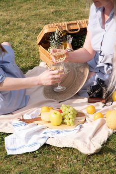 a two young women in a summer long dresses is resting on a picnic, a Blanket with cheese plate and fruits, rest from worries and household chores, parks and recreation areas,.High quality photo