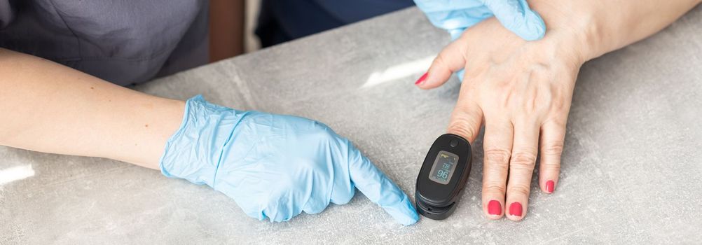 Nurse uses pulse oximeter to measure elderly patient's blood oxygen saturation.