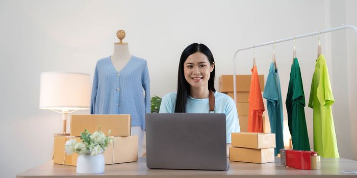 Young woman small business owner working at home office. Online marketing packaging delivery, startup SME entrepreneur or freelance woman concept.