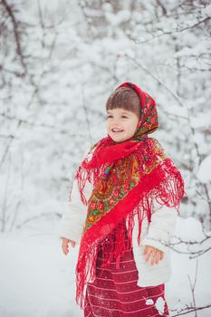 Beautiful little girl in old Russian clothes in a winter forest.