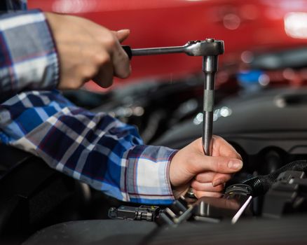 Female auto mechanic unscrewing a nut to replace a car spark plug