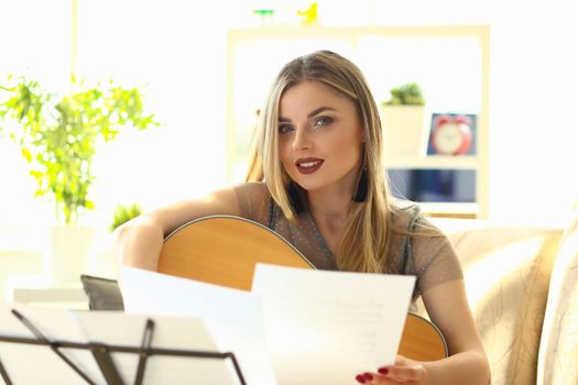 Beautiful woman is holding guitar and notes. Learning to play guitar concept