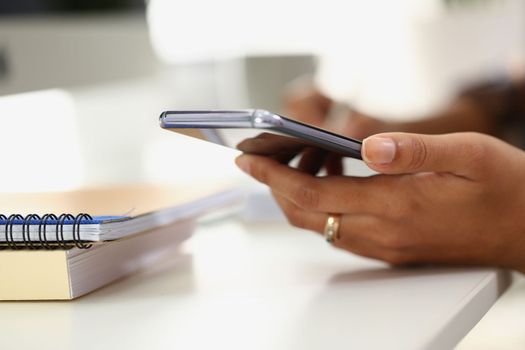 Woman writes on notebook with pen and holds smartphone. Apps for notes and reminders concept